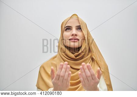 Portrait of young muslim woman making dua, praying to God