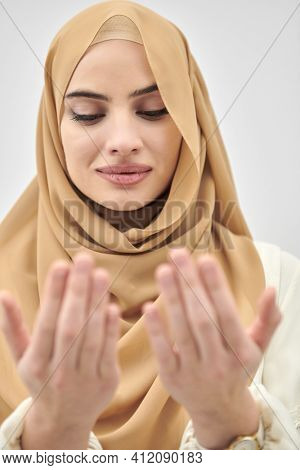 Portrait of young muslim woman making dua, praying to God