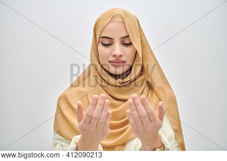 Portrait of young muslim woman making dua, praying to God