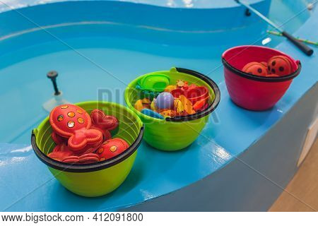 Fishing In The Paddling Pool. Childrens Toys In The Pool. Toy Fish Fishing Rod. Cheerful Children Fi