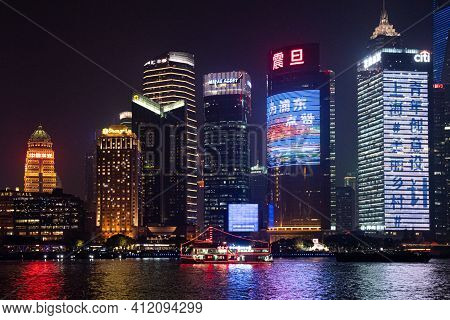 Night Cityscape Of Shanghai View From Bund Waitan Waterfront. Red Neon Lights Of Tourist Ship At Riv