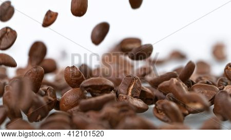 Falling Roasted Coffee Beans on White Background, close-up.