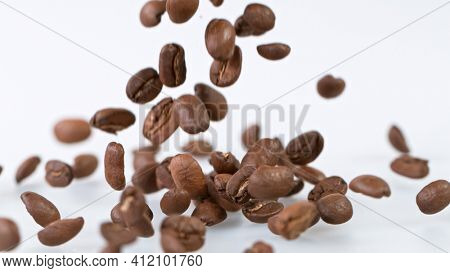 Falling Roasted Coffee Beans on White Background, close-up.
