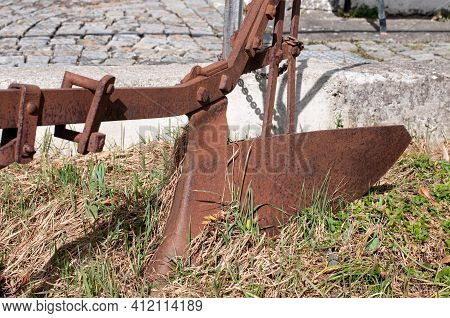 A Vintage Ploughshare In The Garden Of An Old Farmhouse