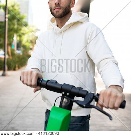 Man with hoodie rining an electric scooter