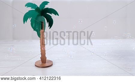 Rtificial Palm Tree And Rainbow Soap Bubbles On A White Wooden Table. Relaxation And Imagination Con