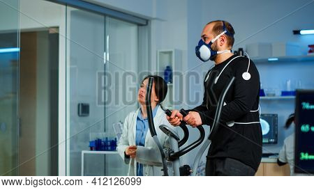 Medical Researcher Talking With Sportsman And Showing Ekg Scan On Virtual Screen While Measuring His