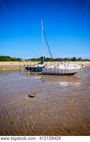 A Sailing Boat And A Motorboat Laying On The Beach At Lowtide On A Sunny Summertime On The Isle Of î