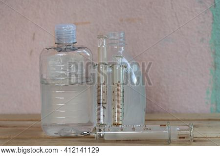 Bottles Of Alcohol Gel And Syringes On Wooden Background