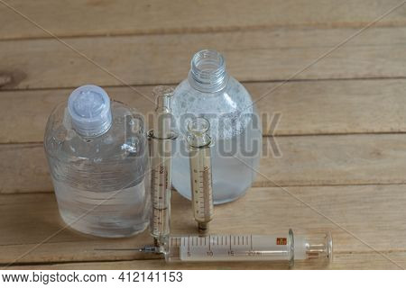 Bottles Of Alcohol Gel And Syringes On Wooden Background