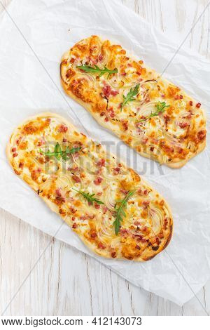Tarte Flambee - flat bread (Flammkuchen) with bacon, onion, champignon and cheese on white background