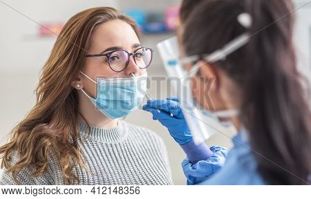 Female Patient Wearing Mask Over Mouth Is Having Sample Taken From Nose For A Pcr Test For Covid 19.