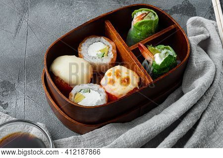 Japanese Meal In A Box Bento With Sushi Roll Eice Avocado Salmon Fish Set, On Gray Stone Background 