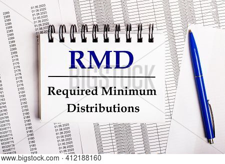 On The Table Are Charts And Reports, On Which Lie A Blue Pen And A Notebook With The Word Rmd Requir
