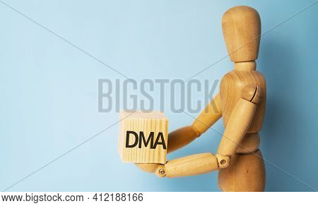 Wooden Man Holding A Wooden Cube With Acronym Dma-direct Market Access. Business And Finances Concep