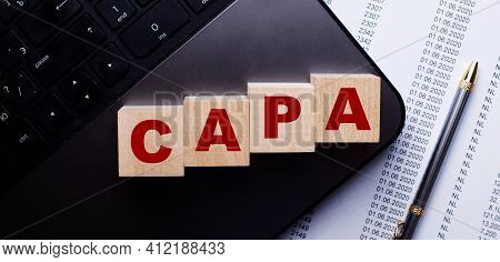 The Word Capa Is Written On Wooden Cubes On The Keyboard Next To The Pen.