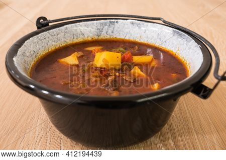 Hungarian Beef Goulash Or Gulyas Soup Or Stew Served In A Small Cauldron With Potatoes, Meat, Paprik