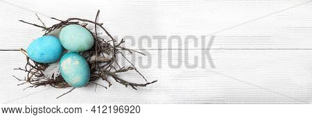 Easter Background With Easter Eggs Nest And Twigs On A Painted Wooden Background. Top View With Copy
