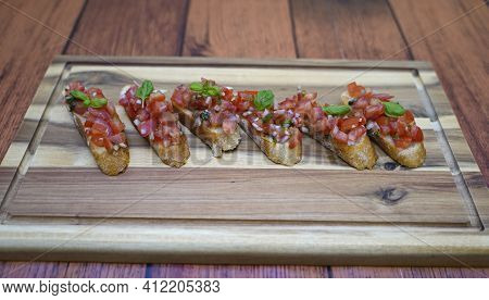 Ready Prepared Bruscetta Arranged On A Wooden Board.