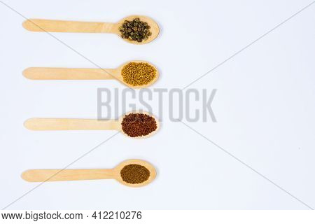 Various Seeds In Wooden Spoons On A White Background. Seeds Of Beet, Mustard, Lettuce, Arugula, On A