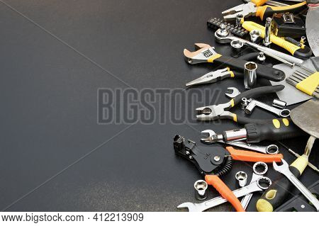Handyman Tool Kit On Black Wooden Table. Many Wrenches And Screwdrivers, Pilers And Other Tools For 