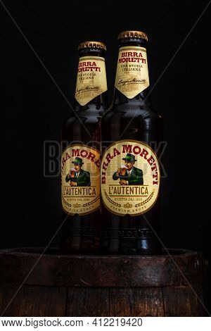 Bottle Of Birra Moretti Beer On Wooden Barrel With Dark Background. Illustrative Editorial Photo Buc