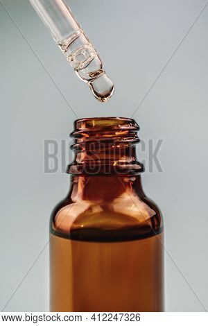 Pipette With Cosmetic Oil Over A Brown Bottle