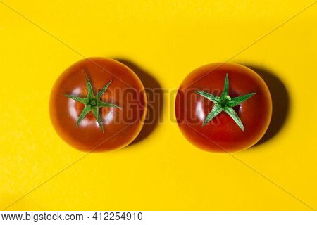 Two Tomatoes With Green Tails Isolated On Yellow Background