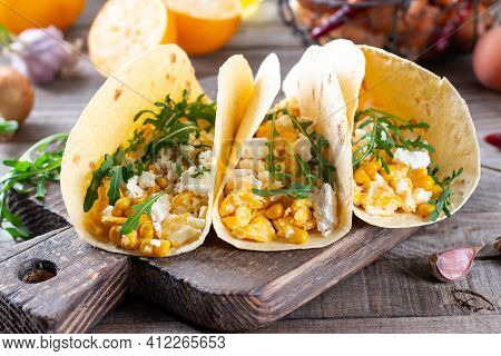 Birria Tacos With Egg, Corn, Cheese And Vegetables On A Wooden Table