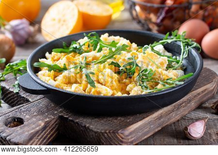Scrumble Eggs With Corn, Cream Cheese Sauce, Herbs And Vegetable Served In Cast Iron Skillet. Delici