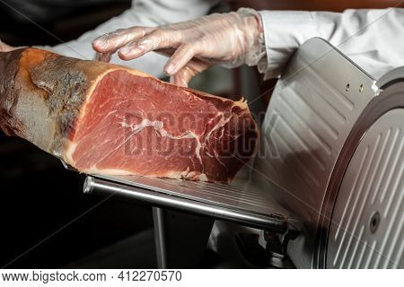 Slicing Hamon On Cutting Machine. Iberian Ham Cutter On Black Background.
