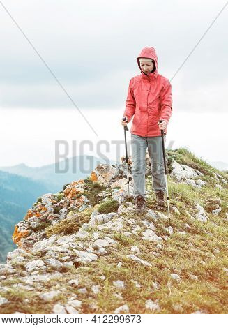 Hiker Young Woman With Trekking Poles Walking On Mountain Ridge In Summer.