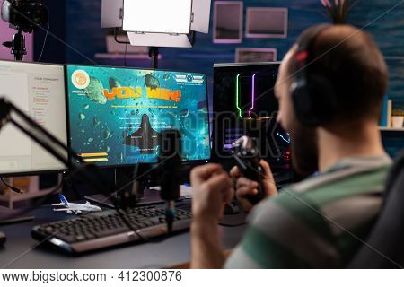 Over Shoulder Footage Of Professional Streamer Playing Digital Videogames On Computer Using Headphon