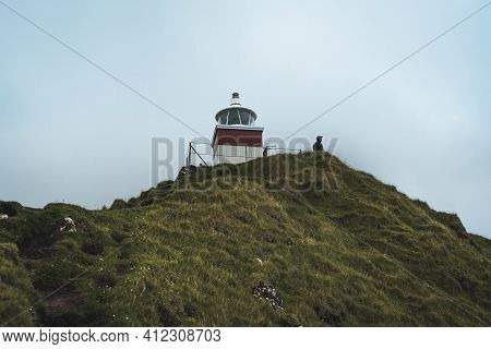 Kalsoy Island With Kallur Lighthouse On On Faroe Islands, Denmark, Europe. Clouds Over High Cliffs, 