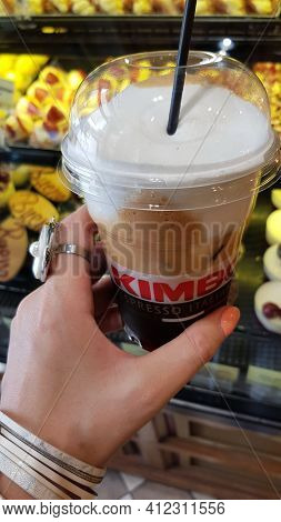 Freddo Cappuccino In Big Takeout Cup With Bakery Showcase Background. Cold Coffee With Fat Milk Foam