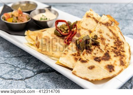 Stuffed Quesadilla Halves On A Plate Topped With Chopped Jalepeno Peppers Roasted To Perfection.