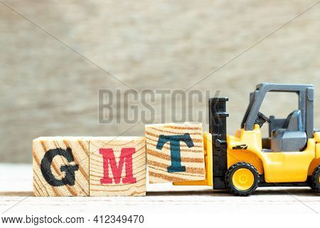 Toy Forklift Hold Letter Block T To Complete Word Gmt (abbreviation Of Greenwich Mean Time)  On Wood