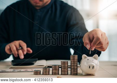 Businessman Holding Coins Putting In Piggy Mank. Concept Saving Money And Finance Accounting For The