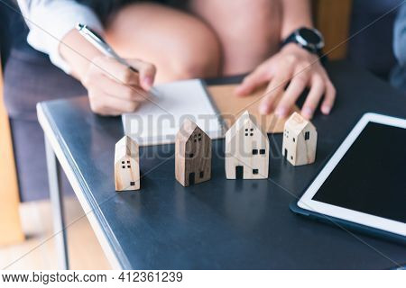 Wooden Toy House Medel With Woman Plan To Sign A Contract To Buy A House, Real Estate Concept.