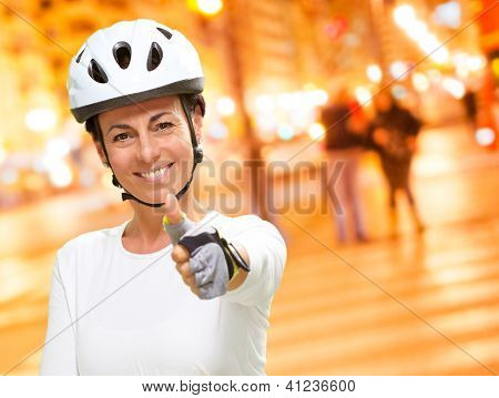 Femme portant casque montrant le pouce vers le haut, en plein air