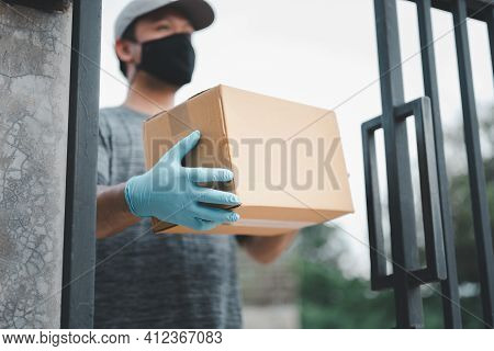New Normal Life Style. Home Delivery Shopping Box Man Wearing Gloves And Protective Mask Delivering 