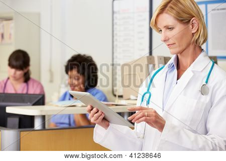 Ärztin, die mit digitalen Tablet bei Krankenschwestern Station