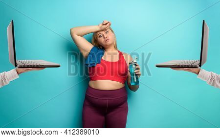 Fat Girl Does Gym At Home Remotely With Laptop. Tired Expression. Cyan Background