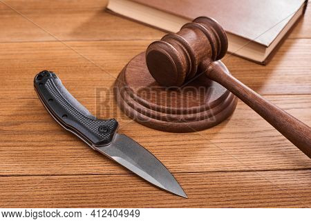 A Folding Knife, A Judge S Gavel And A Book On Wooden Table