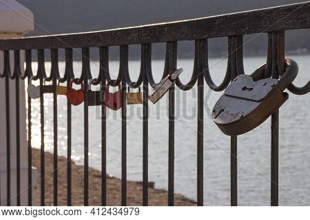 Padlocks On The Railing Of The Bridge As A Symbol Of Love. Selective Focus On A Large Black Barn Cas