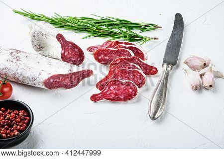 Sliced Cuts Of Longaniza, Dry Cured Spanish  Sausage With Herbs And Spices On White Surface.