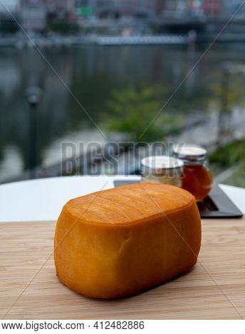 Block Of Belgian Abbey Cheese Made With Brown Trappist Beer And View On Maas River In Dinant, Wallon