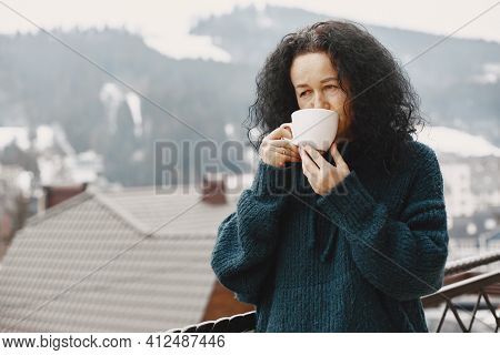 Middle-aged Woman Drinking Coffee On Balcony In Winter Alone
