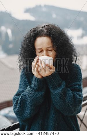 Middle-aged Woman Drinking Coffee On Balcony In Winter Alone