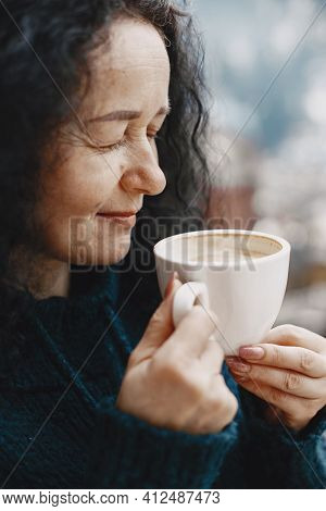 Middle-aged Woman Drinking Coffee On Balcony In Winter Alone